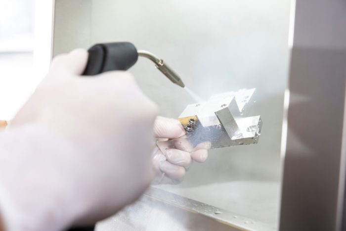 Manuelle Reinigung eines Präzisionsbauteils in der industriellen Auftragsfertigung für Hightech-Anwendungen.